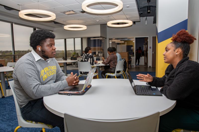 Two students talk while seated at a table in the Eagle Achievement Center