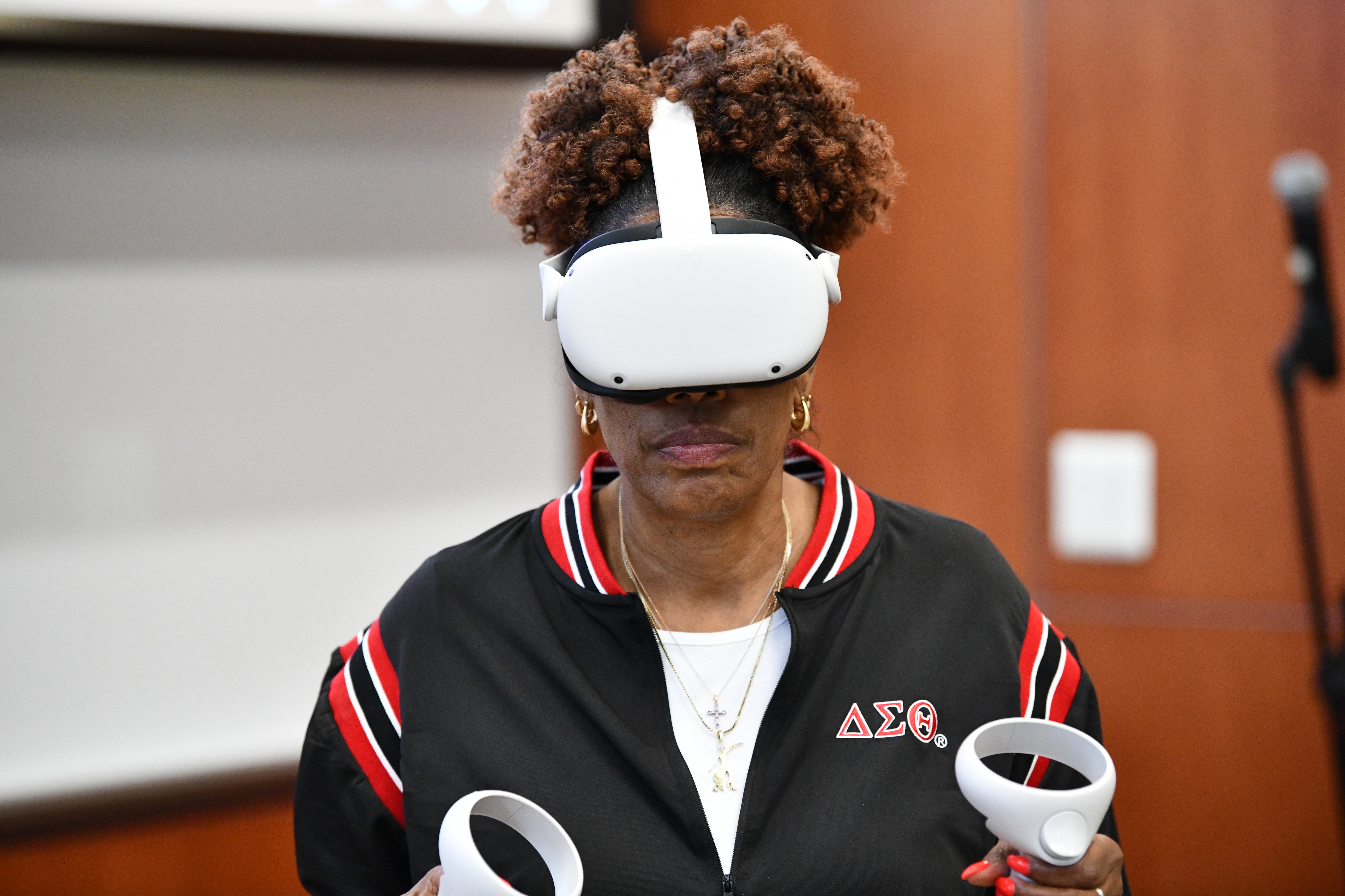 A faculty member uses a virtual reality headset and controllers