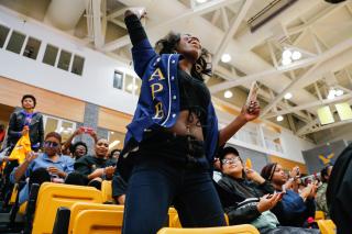 A student wearing a Student Activities Programming Board shirt cheers during an event in the arena